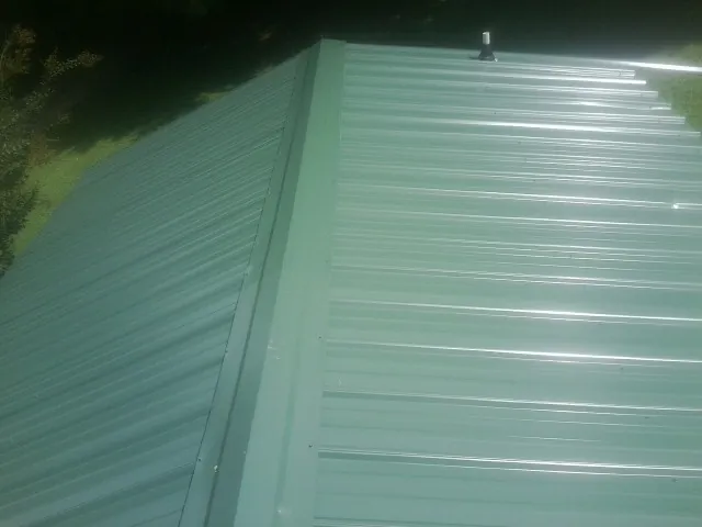 New green metal panels meeting at the ridge of a roof — Flat Roof Repair work by our crew in Indiantown