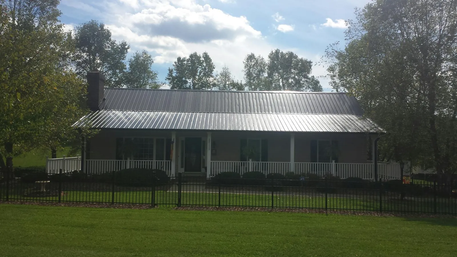 Gray metal roof on a brick ranch with a full width front porch — Gutter Guard Installation work by our crew in Indiantown